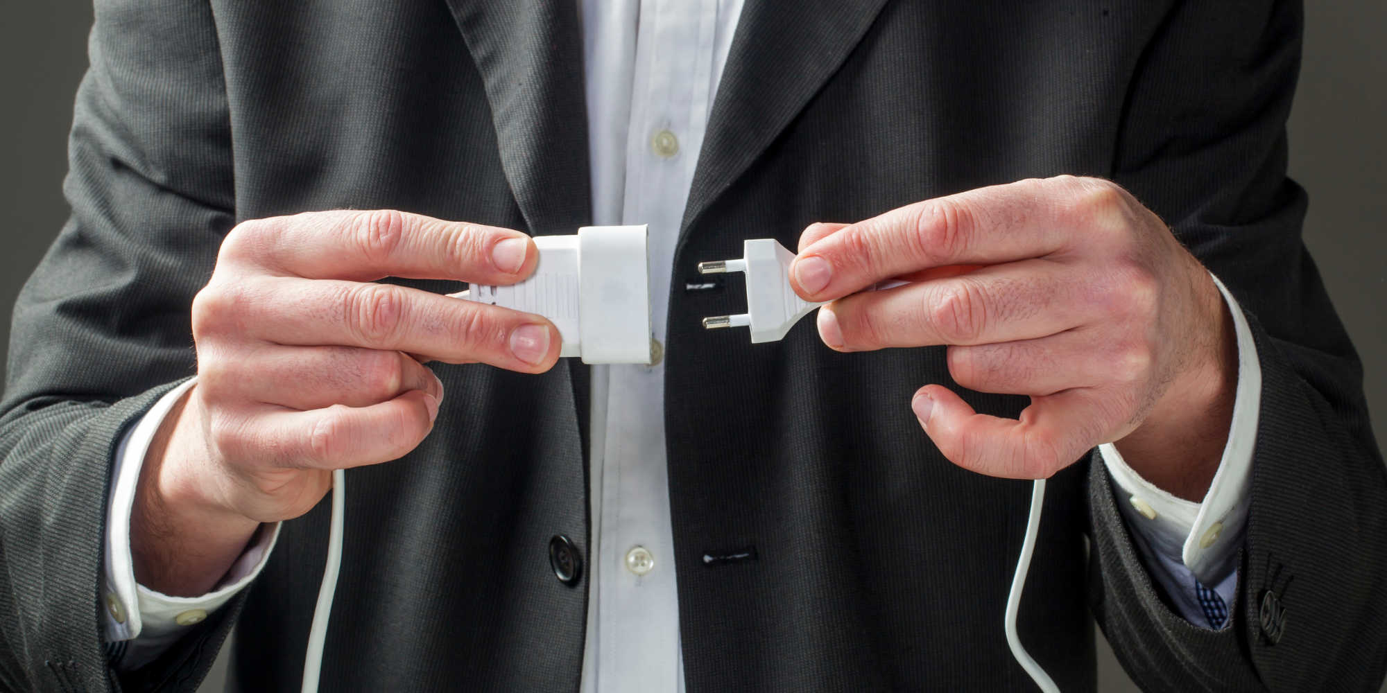 Man in suit holding disconnected plug and outlet 